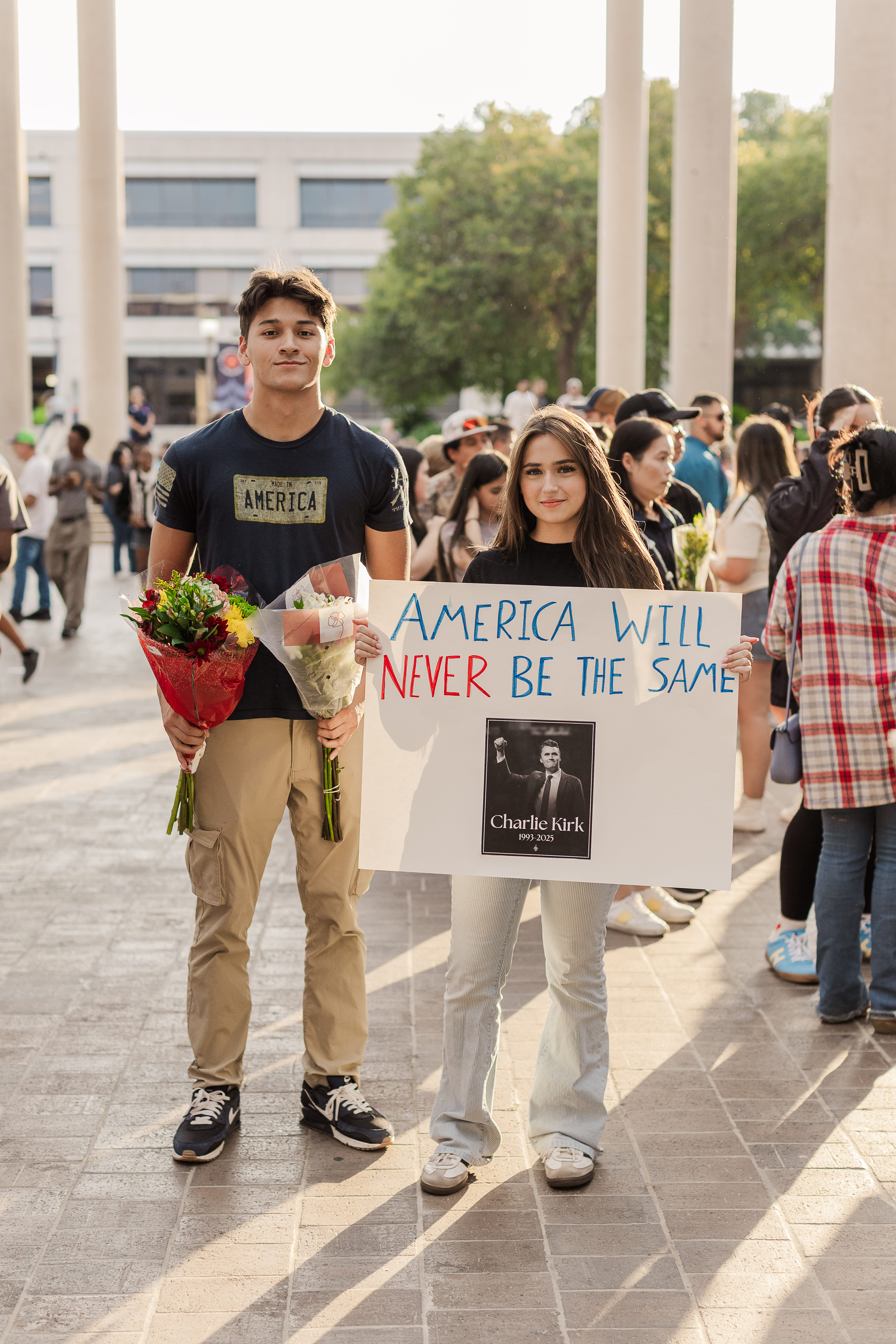 參與學生們舉起呼籲美國和平、悼念查理．柯克的標語，同時獻上鮮花。　圖／維多利亞．賓克利提供