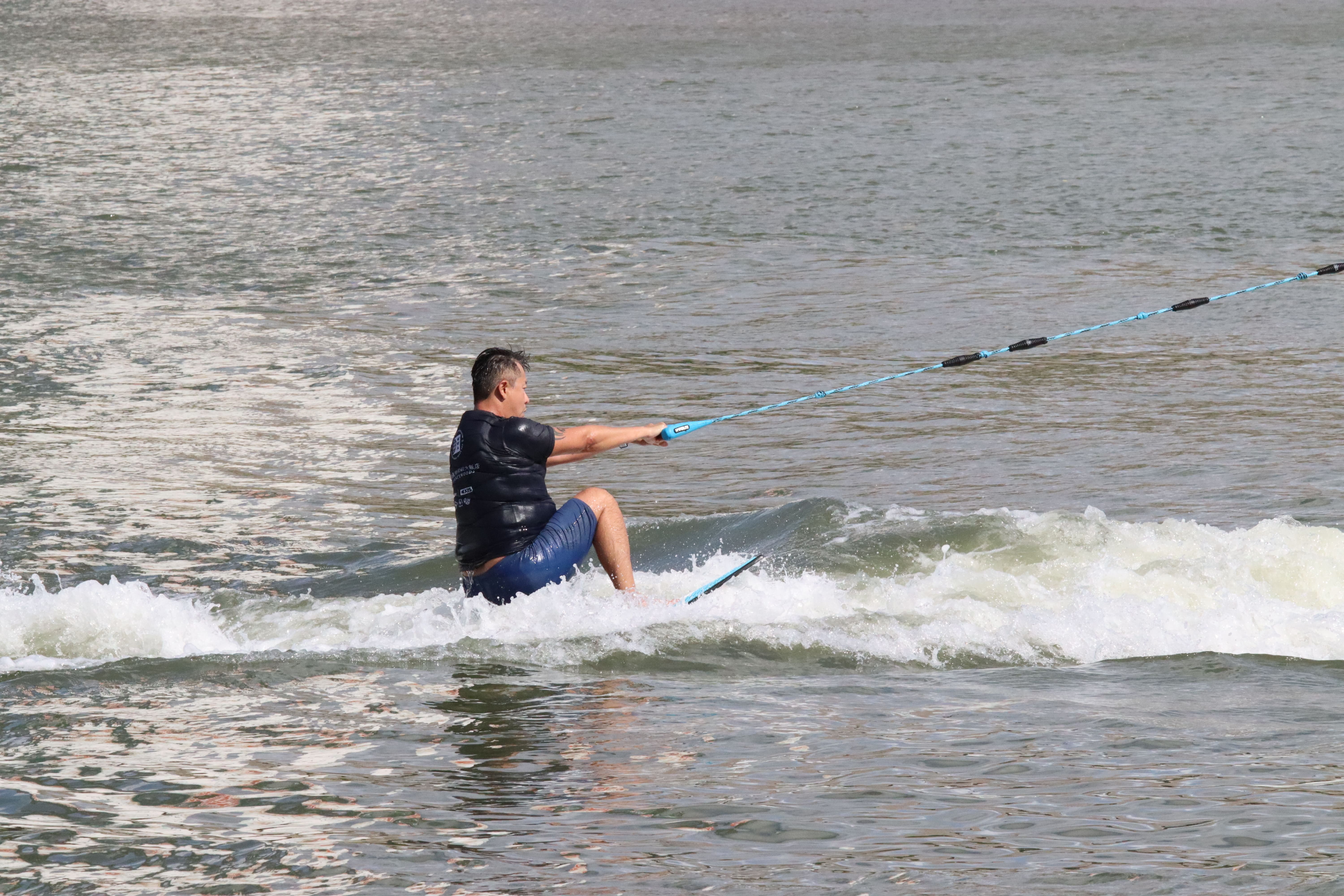 在快艇衝浪的「起水」動作中，滑水者在感覺到握把拉力時，若將雙腿下壓、施重力於中心，板面便會順勢貼合腳底。　圖／呂詠倢攝
