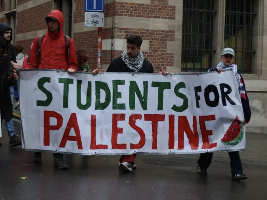 人們共同舉著「學生聲援巴勒斯坦行動」旗幟參與抗議遊行。　圖／Solidarity with Palestine Leuven LAP提供