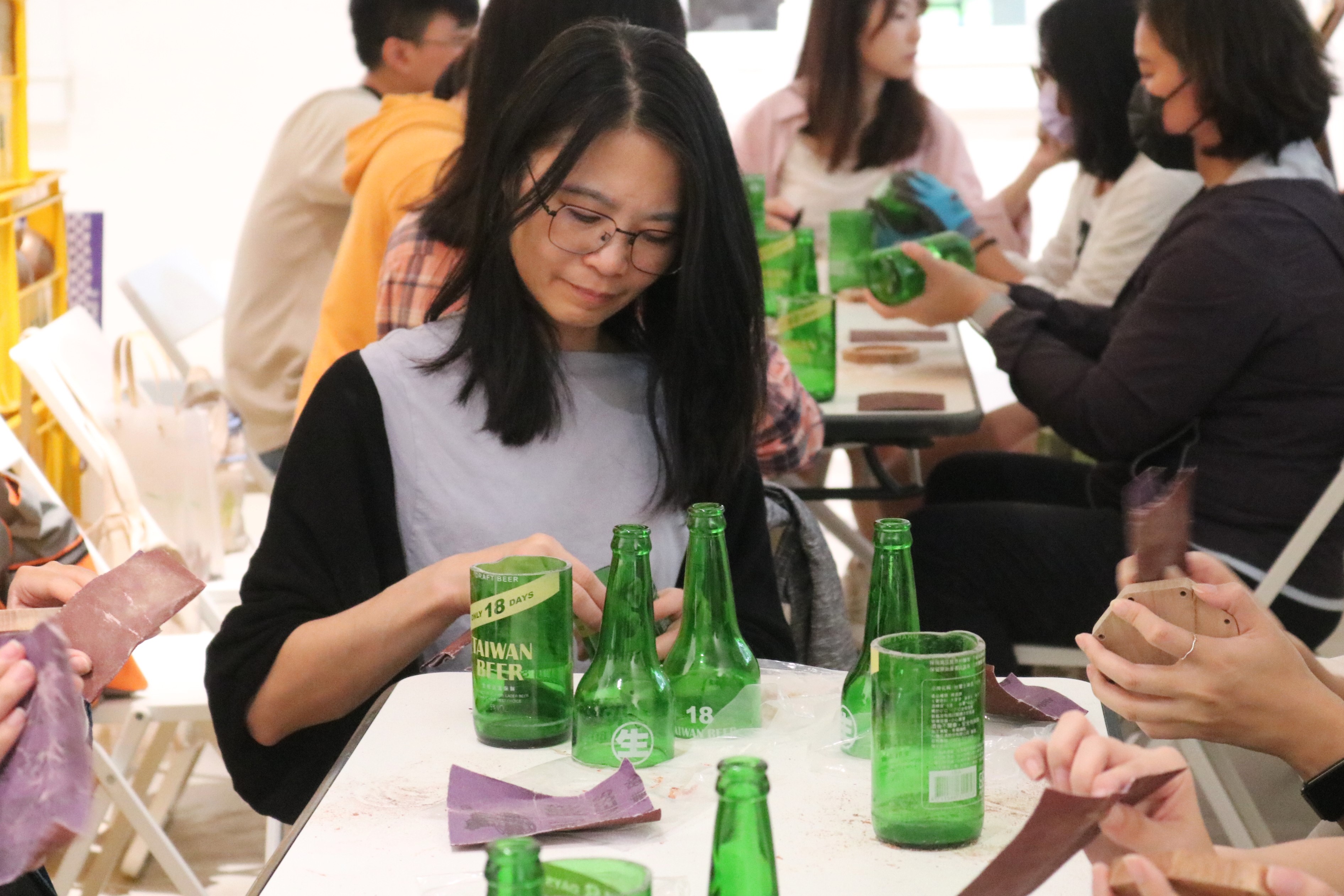 參加者使用不同粗細的砂紙打磨啤酒瓶斷裂處，直到瓶口光滑。　圖／丘羨陶攝