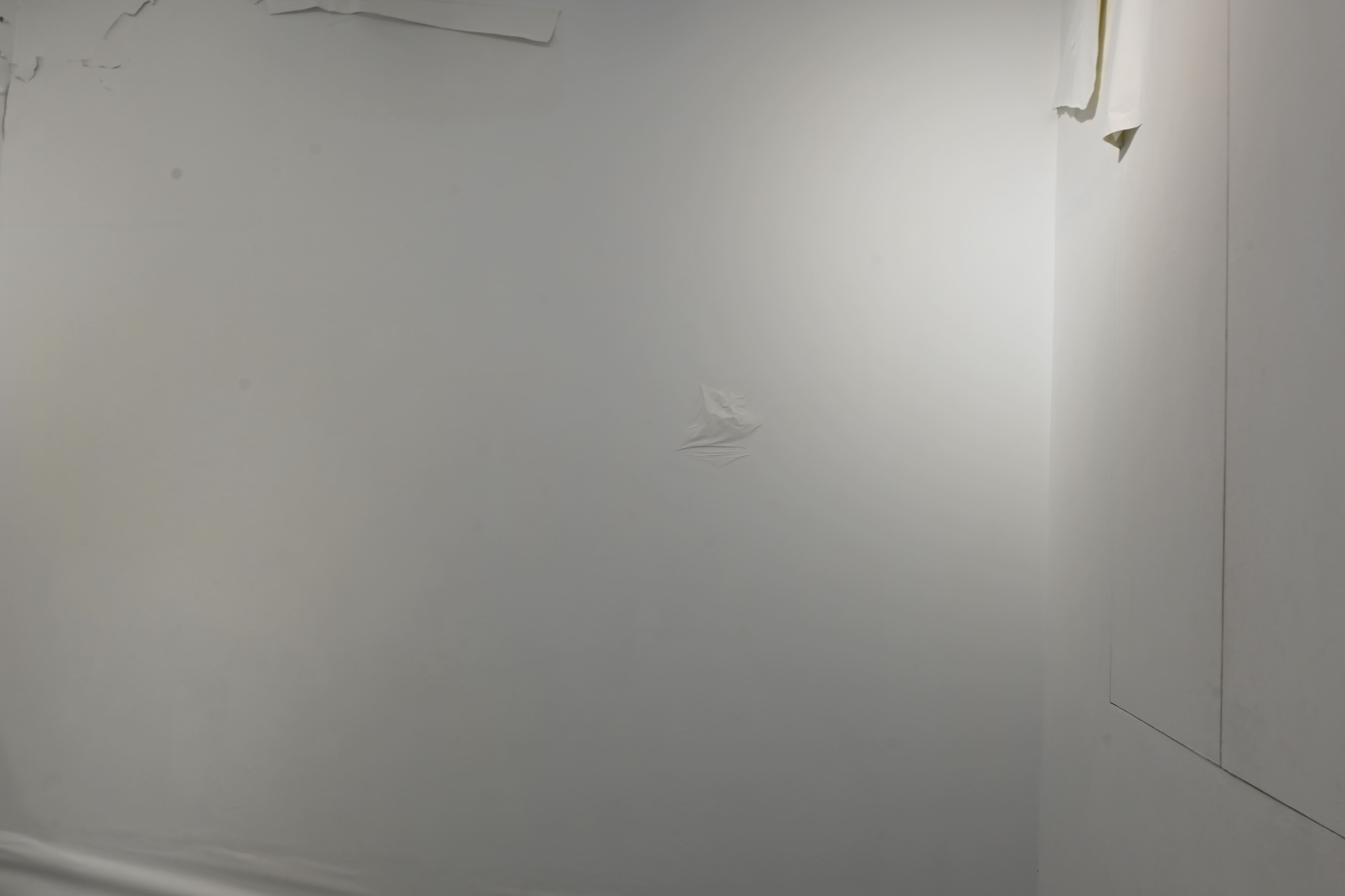展場中原先平整的白牆，被覆蓋一層新的紙材，凸顯出牆面受潮所發生的不同變化。　圖／王翊丞攝
