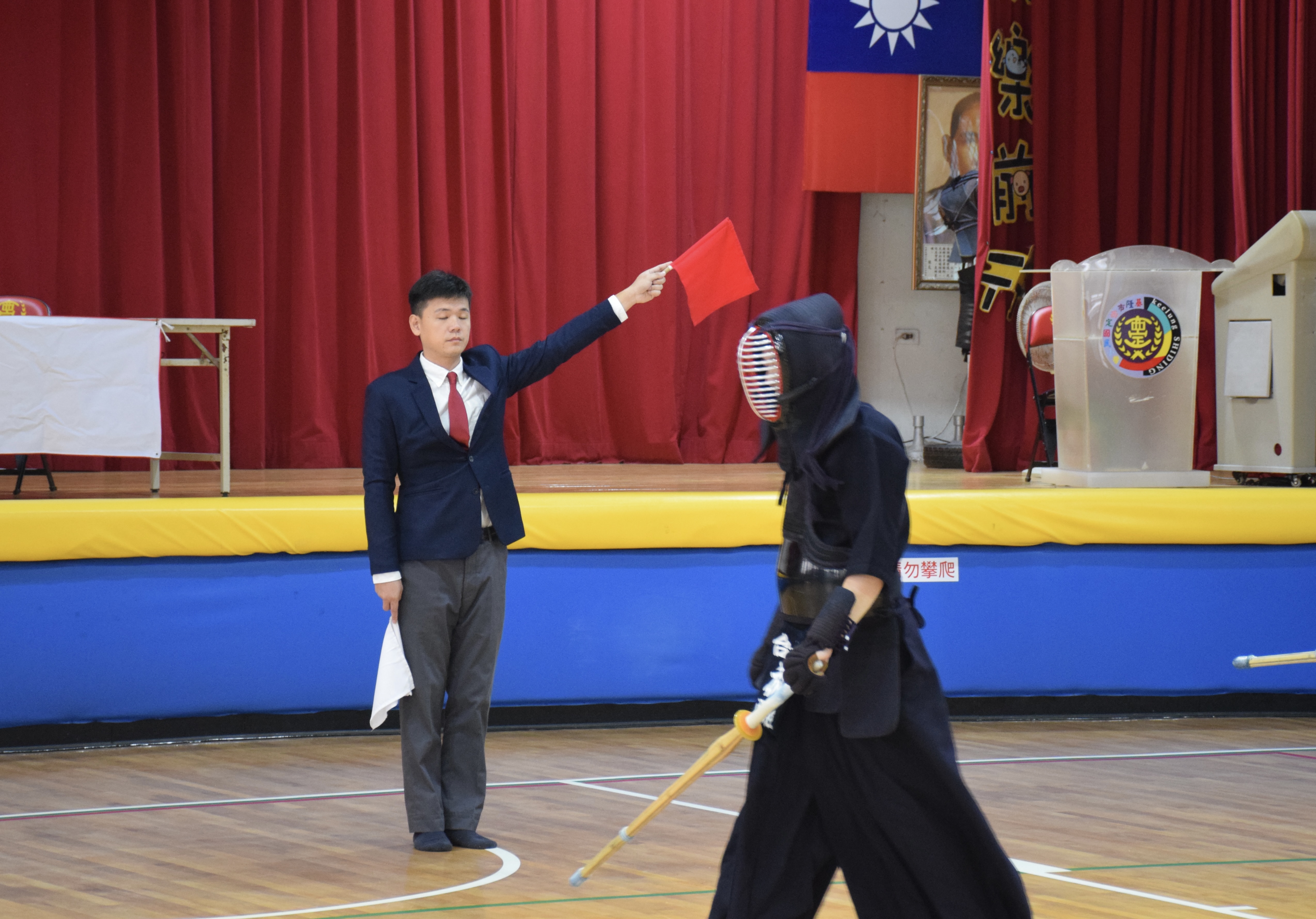 裁判舉起紅旗示意有效擊中，選手步離比賽區域準備下一回合攻勢。　圖／江虹攝