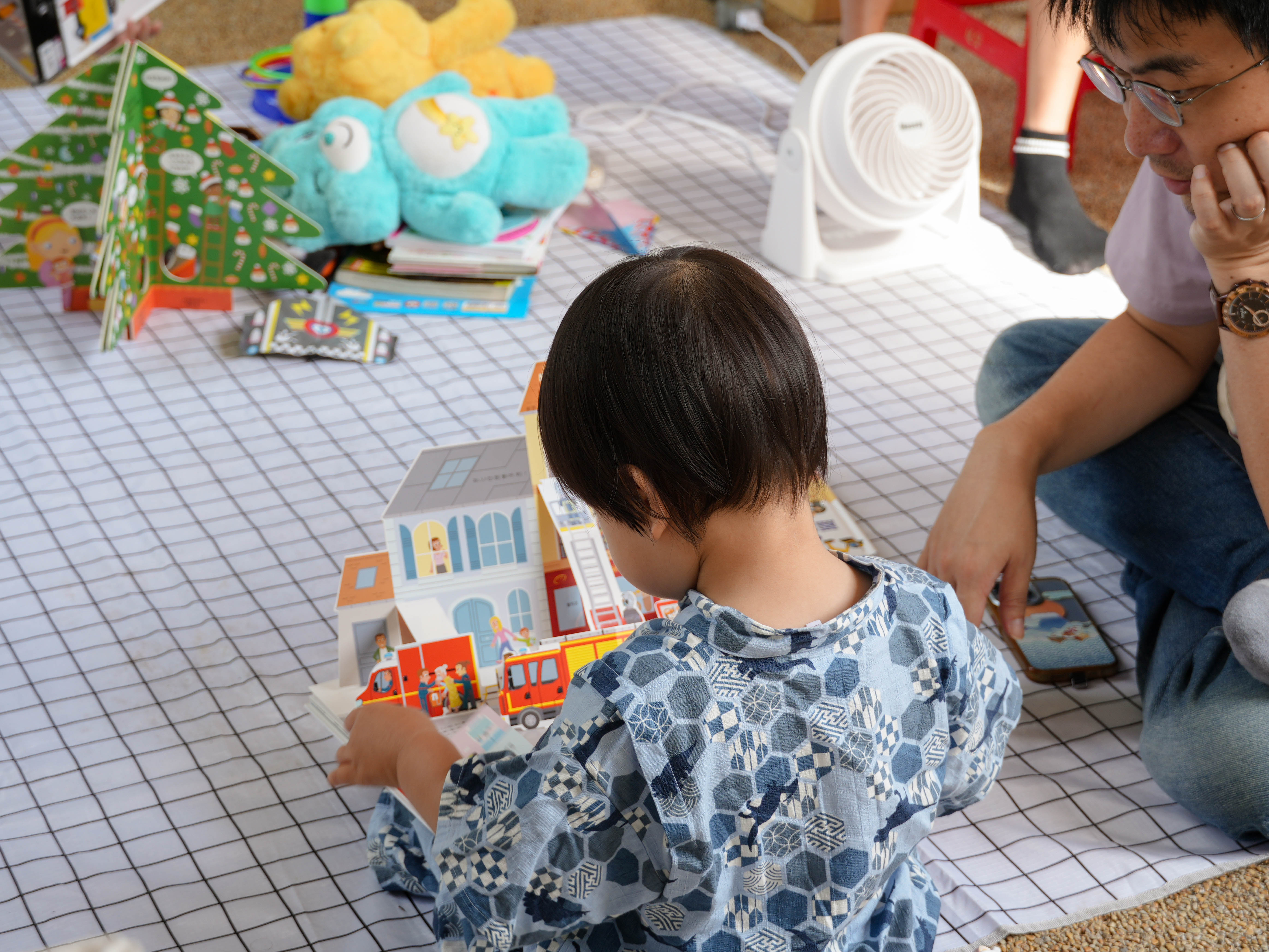 書洞市集闔家共樂，孩童在攤位前閱讀立體書，家長也陪同感受閱讀的樂趣。　圖／黃暐喬攝