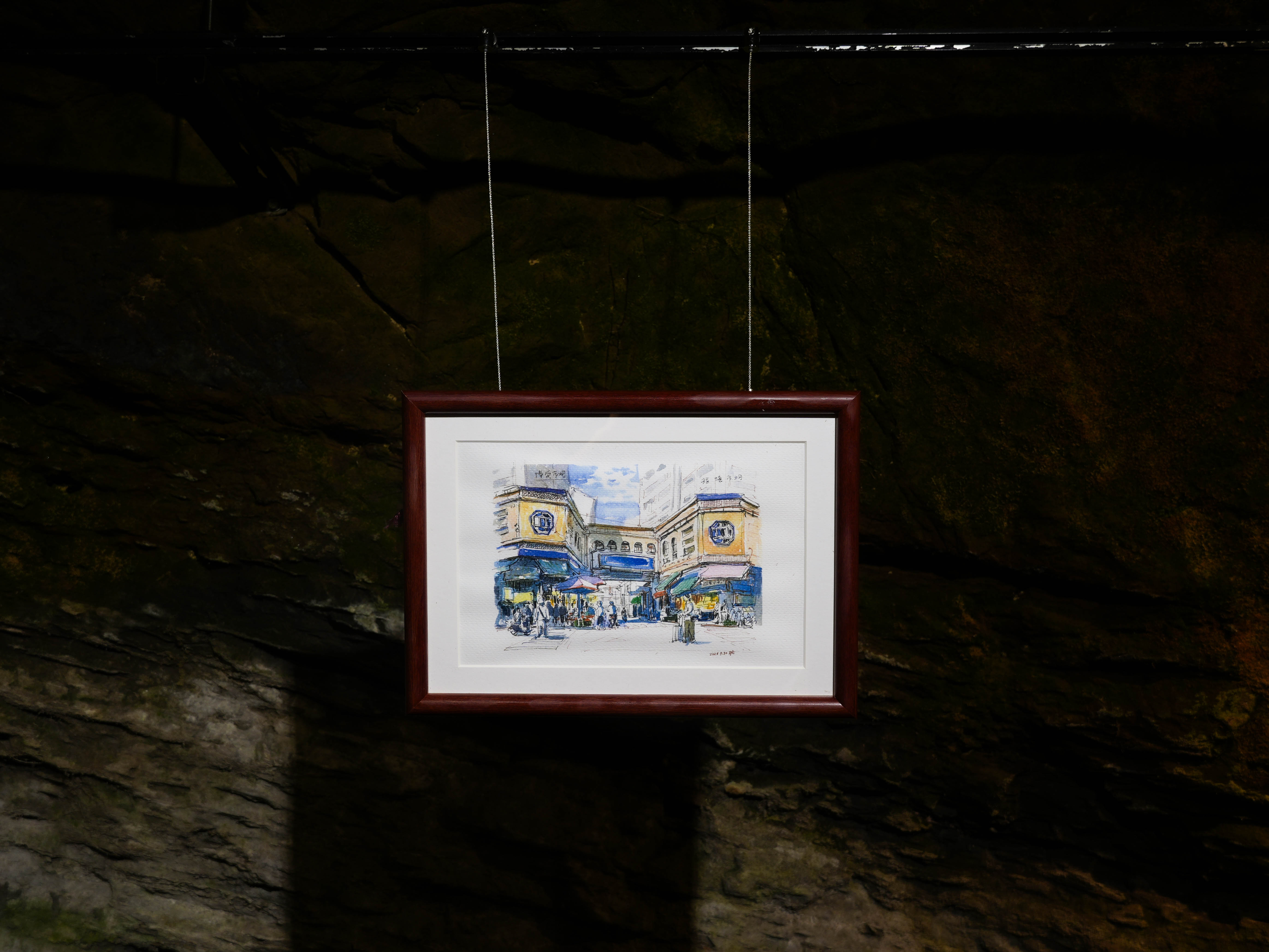 林繼勝以速寫描繪基隆魚市場，作品懸掛於信二防空洞，在幽暗空間中展現城市日常與人文氣息。　圖／黃暐喬攝