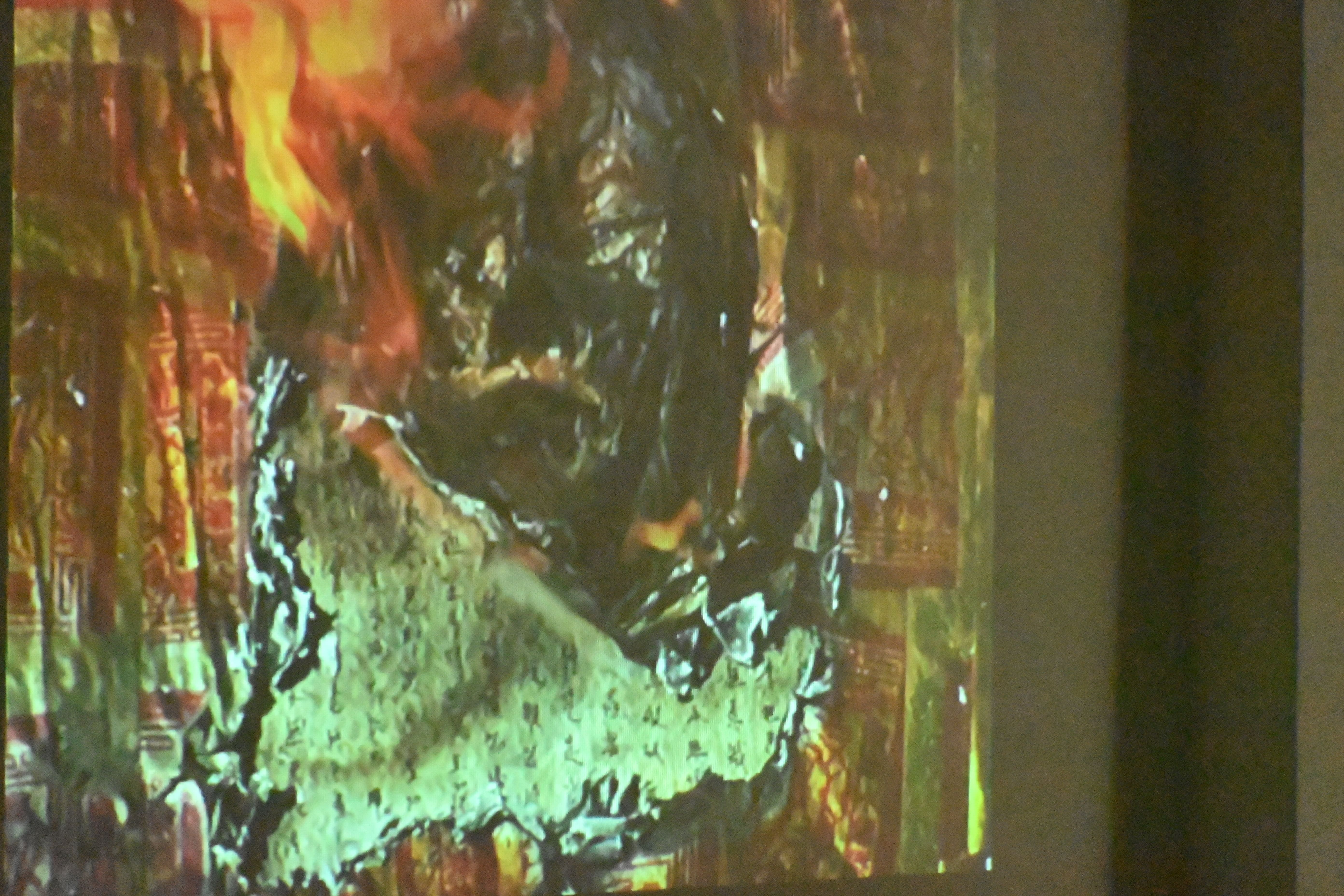 影像作品〈新生〉呈現人臉面具從開始燃燒到結束的過程，金紙覆蓋於面具之上，引發觀眾不同的想像。　圖／林庭如攝