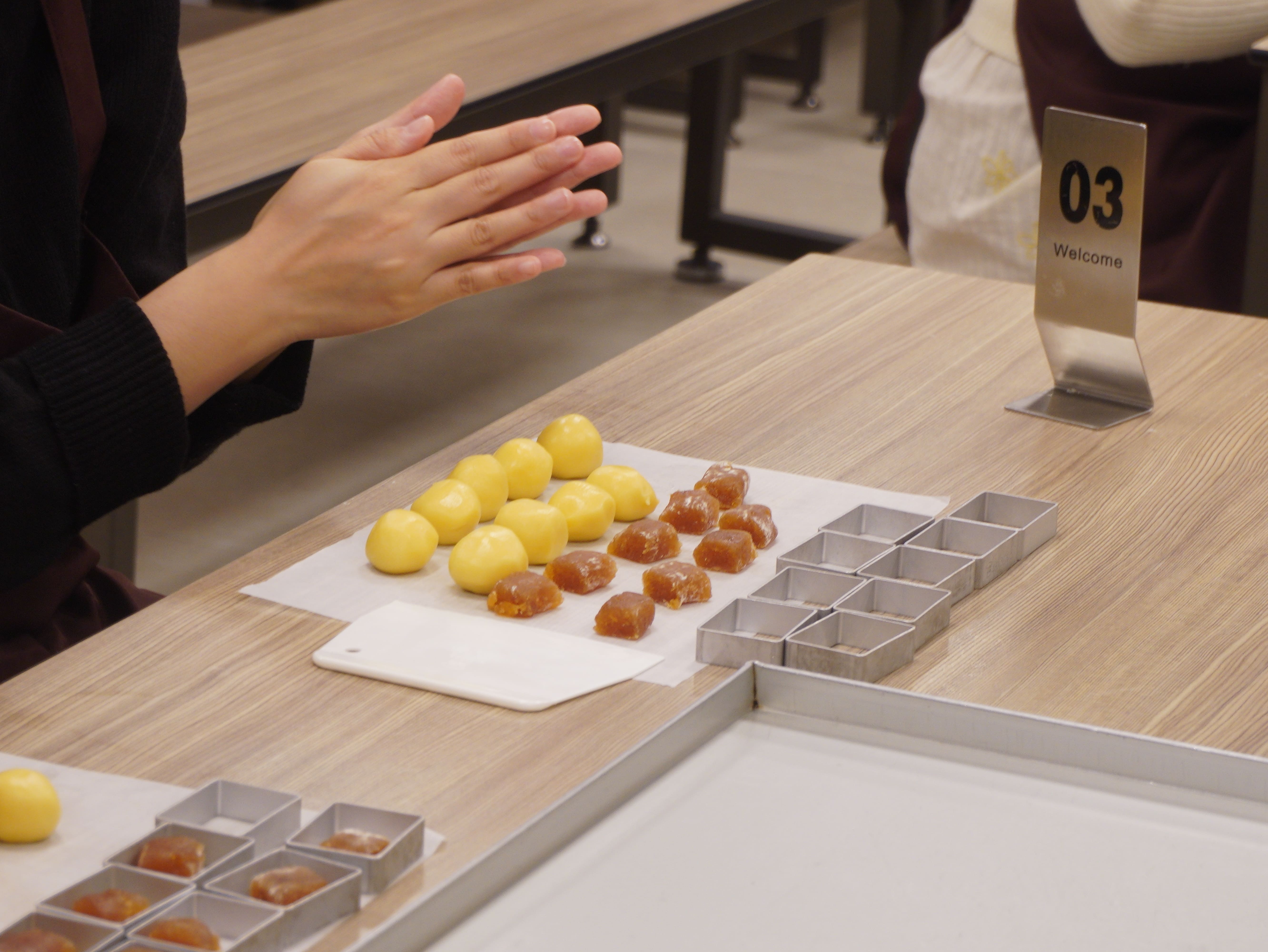 參與學生親手揉捏麵團，包入鳳梨餡後壓入方形模具。　圖／黃千艾攝