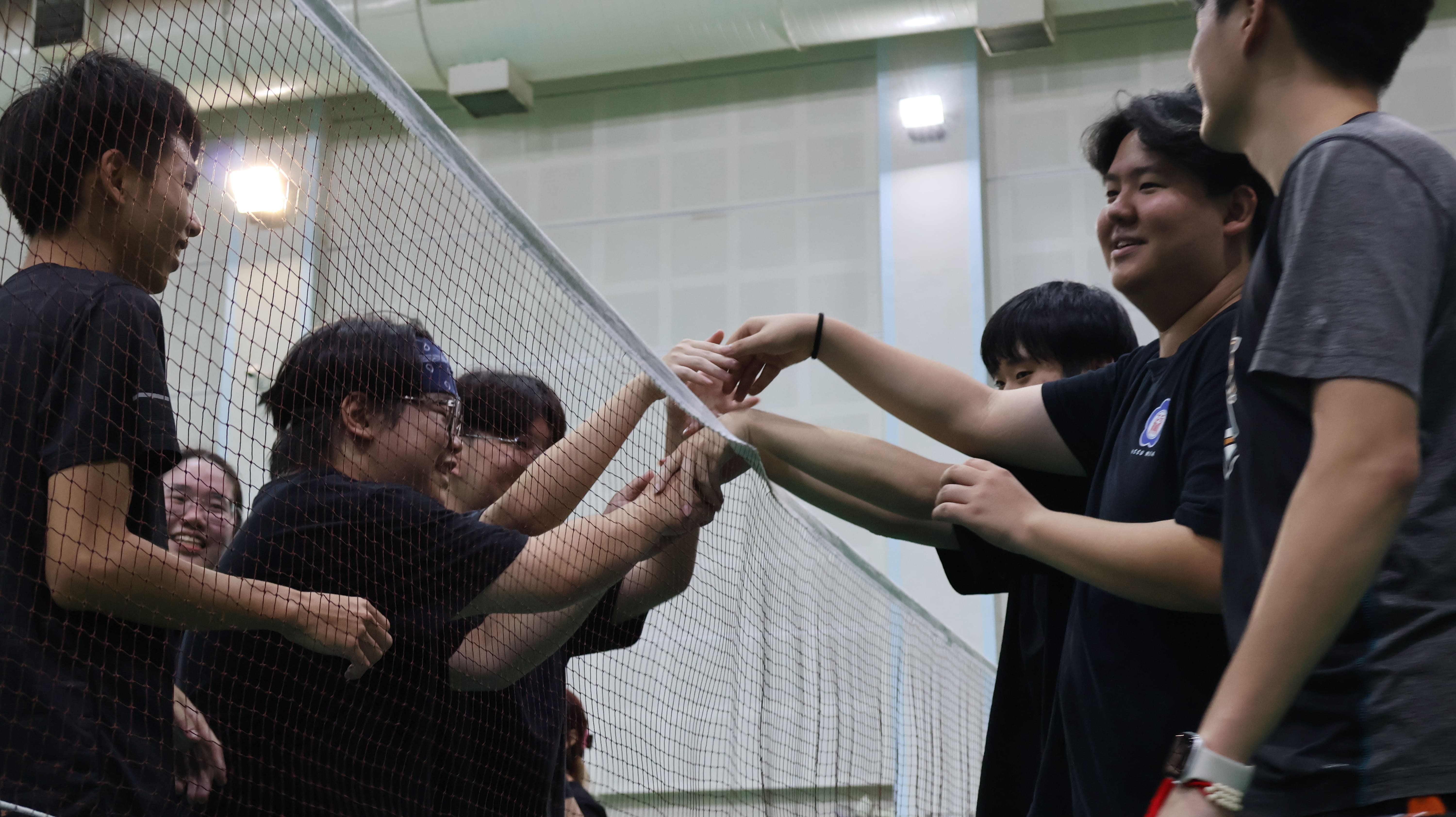 羽球賽結束後，兩隊選手在網前握手致意，展現競賽中的友誼與體育精神。　圖／顏貝恩攝