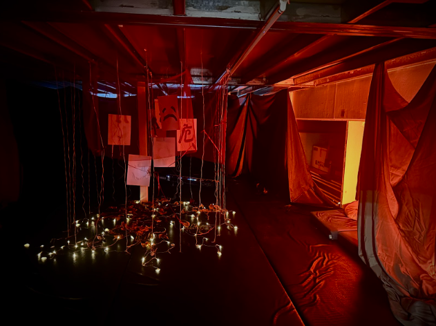 「夢．見」懸掛圖像與燈串營造詭異壓迫感來呈現噩夢，在幽暗空間與橘光交錯間領觀眾重新審視自己的夢境。　圖／劉倚瑄攝